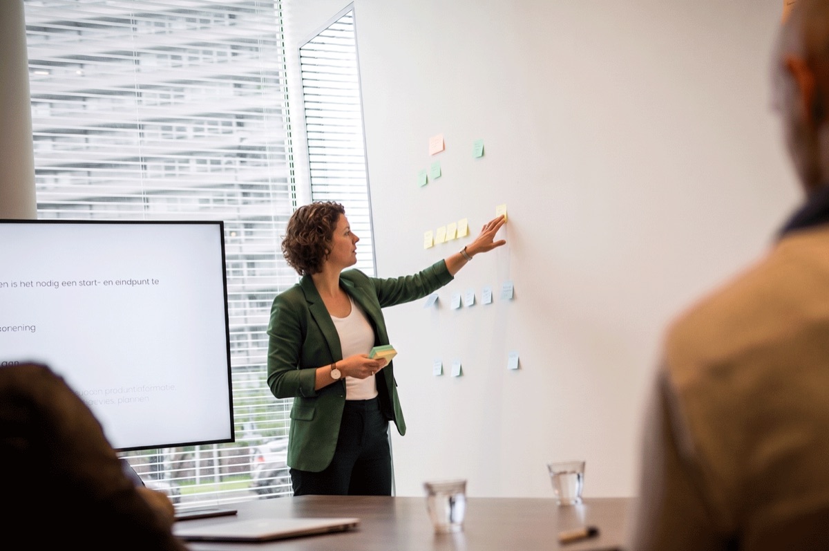 Vrouw plakt tijdens een werksessie post-its op een wand